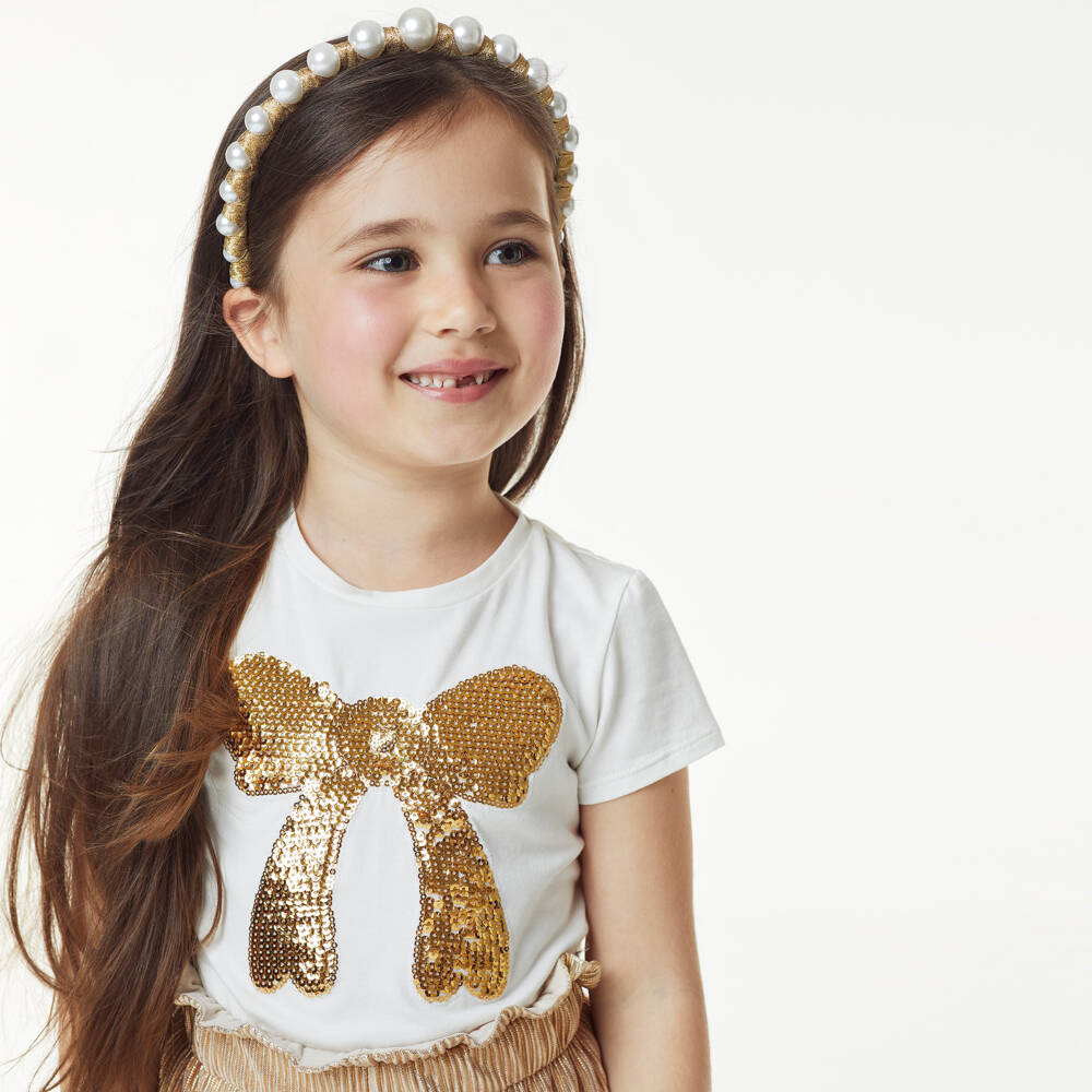 تشلدرن صالون-تيشيرت قطن جيرسي مزين بفيونكة ترتر لون عاجي وذهبي للبنات | Childrensalon Outlet